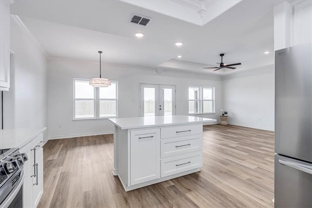 kitchen featuring white cabinetry, a center island, hanging light fixtures, a tray ceiling, and stainless steel appliances