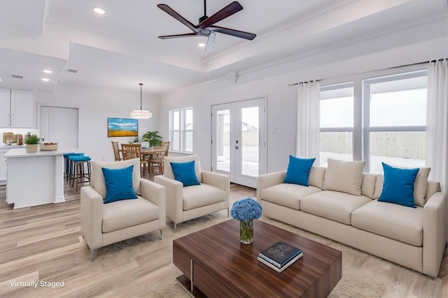 living room featuring crown molding, ceiling fan, a raised ceiling, french doors, and light wood-type flooring