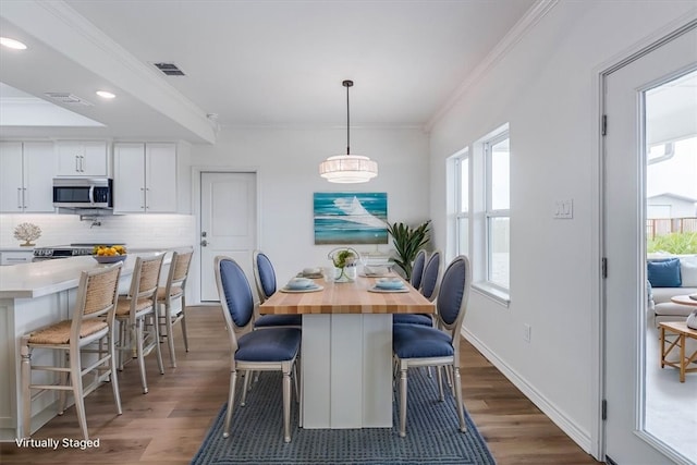 dining room with dark hardwood / wood-style flooring and crown molding