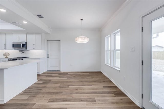 kitchen with light hardwood / wood-style flooring, ornamental molding, white cabinets, pendant lighting, and backsplash