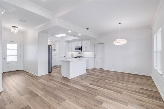 kitchen with white cabinetry, crown molding, decorative light fixtures, a kitchen island, and stainless steel appliances