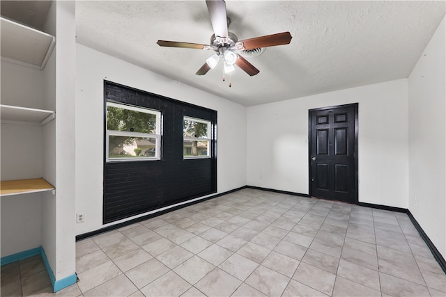 tiled spare room featuring a textured ceiling and ceiling fan