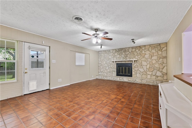 unfurnished living room featuring a fireplace, tile patterned flooring, a textured ceiling, and ceiling fan