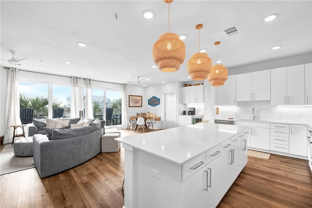 kitchen with a kitchen island, white cabinetry, decorative light fixtures, and dark hardwood / wood-style floors