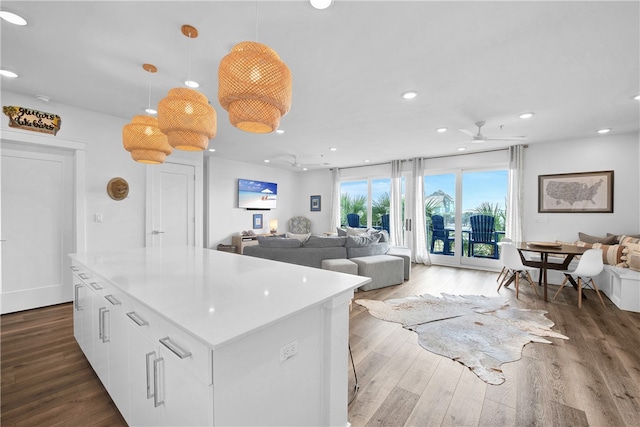 kitchen featuring pendant lighting, ceiling fan, a center island, white cabinets, and dark wood-type flooring