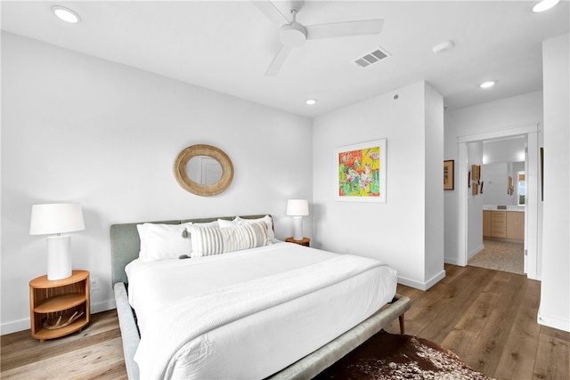 bedroom with light wood-type flooring, ensuite bath, and ceiling fan