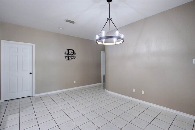 tiled empty room featuring a chandelier