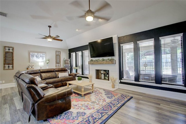 2111 Buckeye Dr, Ingleside, TX 78362 - living area with a ceiling fan, wood finished floors, baseboards, lofted ceiling, and a large fireplace