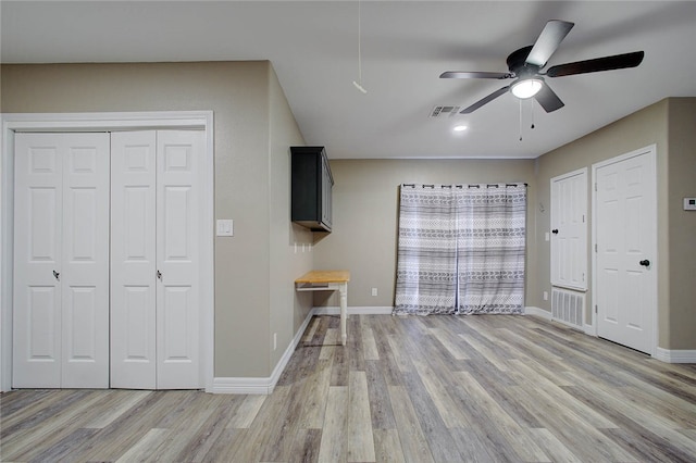 unfurnished bedroom with multiple closets, wood-type flooring, and ceiling fan