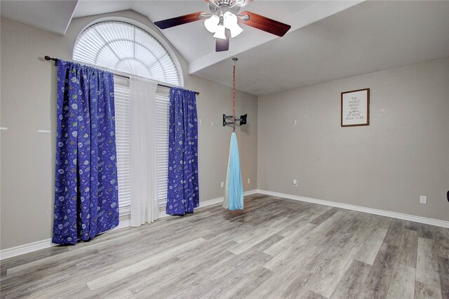 spare room with ceiling fan, vaulted ceiling, and light hardwood / wood-style floors