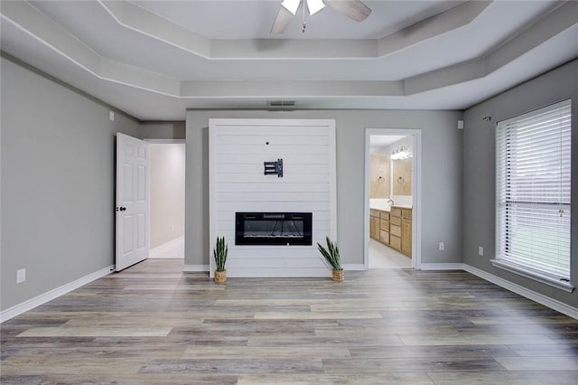 2111 Buckeye Dr, Ingleside, TX 78362 - unfurnished living room with a tray ceiling, ceiling fan, wood finished floors, a fireplace, and baseboards