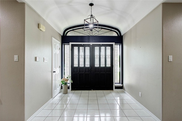 entrance foyer with lofted ceiling, light tile patterned floors, and a notable chandelier