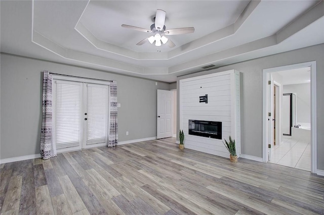 2111 Buckeye Dr, Ingleside, TX 78362 - unfurnished living room featuring a tray ceiling, a ceiling fan, a large fireplace, wood finished floors, and baseboards