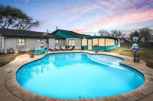 pool at dusk with a patio area