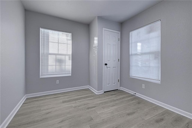 empty room featuring baseboards and light wood finished floors