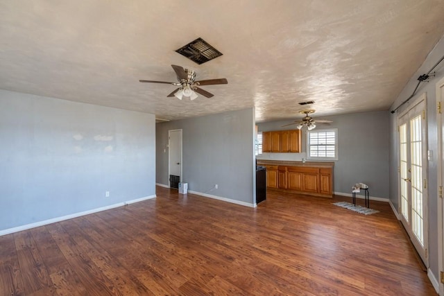 unfurnished living room featuring a textured ceiling, dark hardwood / wood-style floors, and ceiling fan