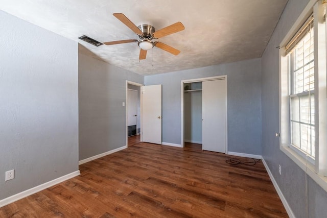 unfurnished bedroom featuring ceiling fan, dark hardwood / wood-style floors, and a closet