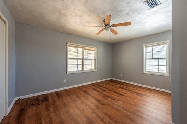 spare room featuring ceiling fan, hardwood / wood-style floors, and a healthy amount of sunlight