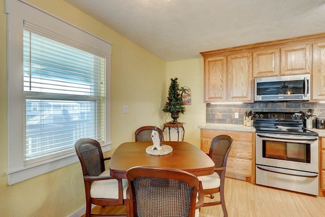 kitchen featuring light wood-type flooring, light brown cabinetry, tasteful backsplash, a healthy amount of sunlight, and stainless steel appliances