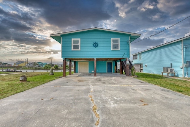 view of front of property featuring a carport, a garage, central air condition unit, and a front yard