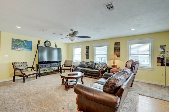 living room with light carpet, a textured ceiling, and ceiling fan