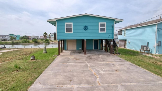 view of front of house featuring a front yard, a water view, a garage, and a carport