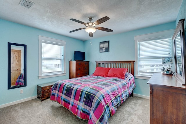 carpeted bedroom with multiple windows, a textured ceiling, and ceiling fan