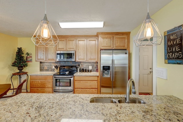 kitchen with light stone countertops, sink, hanging light fixtures, stainless steel appliances, and tasteful backsplash