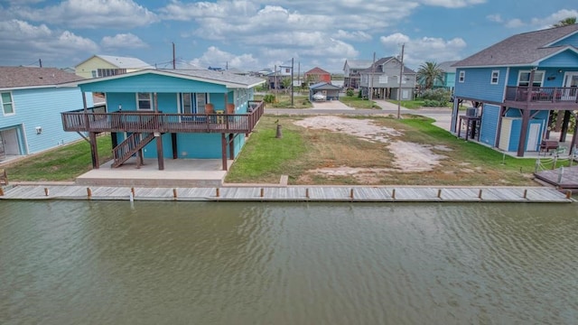 rear view of property featuring a deck with water view and a lawn