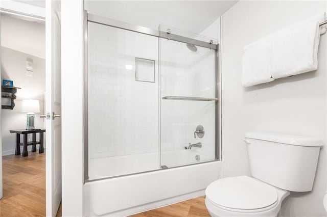 bathroom with toilet, bath / shower combo with glass door, and wood-type flooring