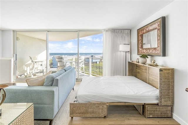 bedroom featuring access to exterior, a water view, and light wood-type flooring