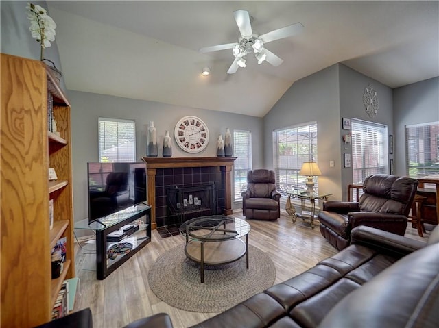 living area featuring ceiling fan, lofted ceiling, a fireplace, and wood finished floors