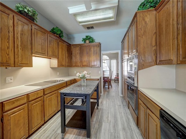 kitchen with brown cabinets, black appliances, visible vents, and light countertops