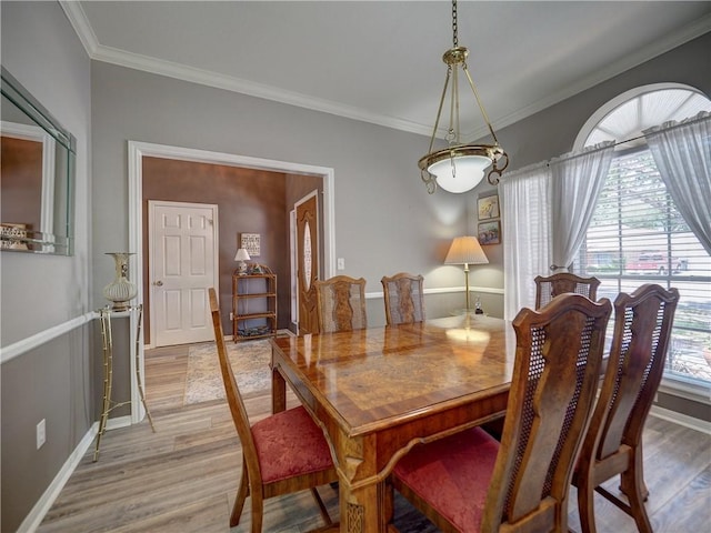 dining room with crown molding, baseboards, and light wood-style floors