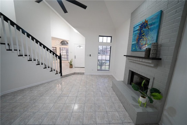 unfurnished living room with a brick fireplace, light tile patterned floors, and high vaulted ceiling