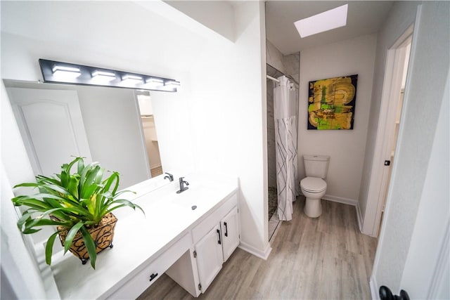 bathroom featuring a skylight, vanity, wood-type flooring, toilet, and walk in shower