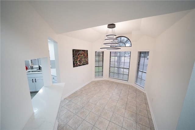 dining space with an inviting chandelier, lofted ceiling, sink, and light tile patterned floors