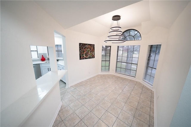 dining area with an inviting chandelier, light tile patterned floors, and vaulted ceiling