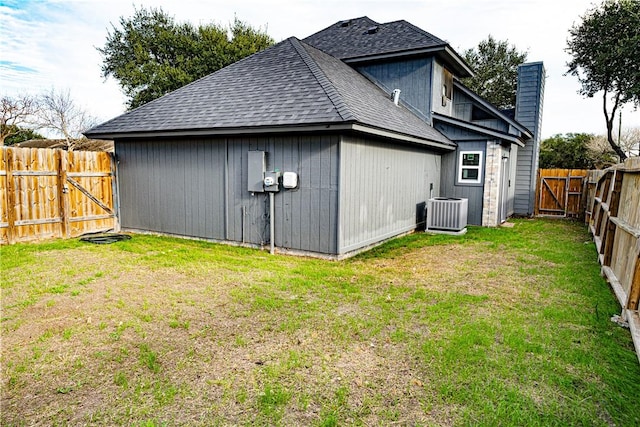 rear view of property featuring a lawn and central air condition unit