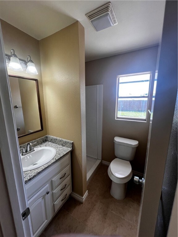 bathroom with toilet, a shower, vanity, and tile patterned floors