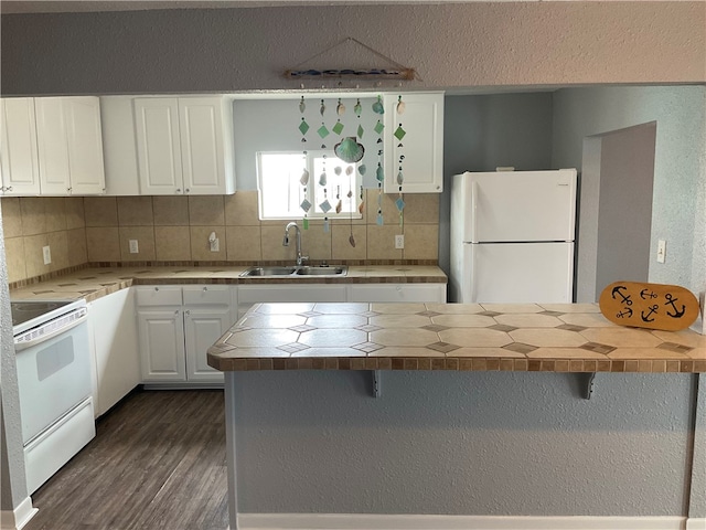 kitchen featuring white appliances, white cabinets, decorative backsplash, sink, and a kitchen breakfast bar