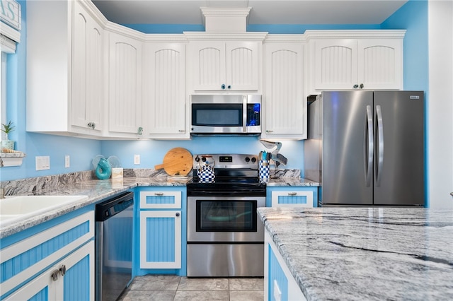 kitchen featuring white cabinets, light stone countertops, light tile patterned floors, and appliances with stainless steel finishes