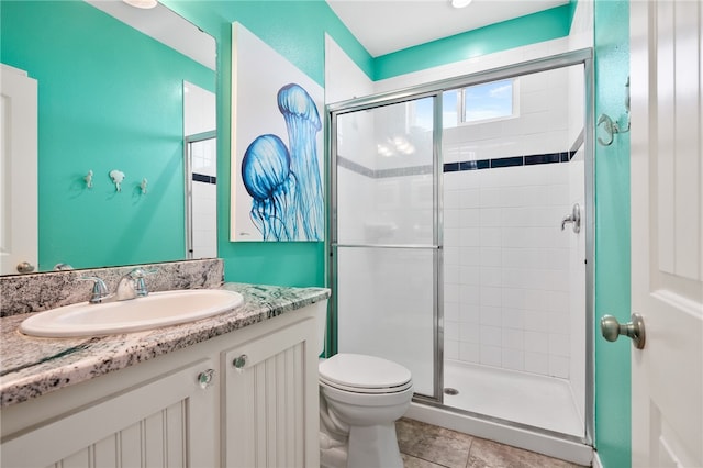 bathroom with vanity, a shower with door, tile patterned flooring, and toilet