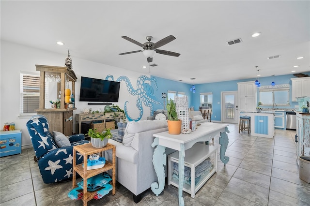 living room featuring ceiling fan, sink, and light tile patterned floors