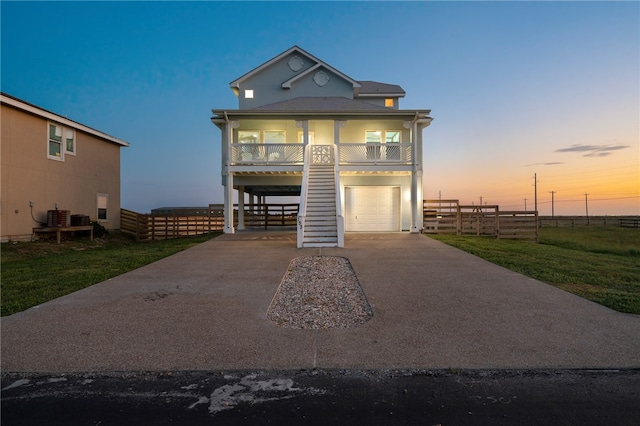 view of front of house with a garage, a porch, central AC unit, and a yard