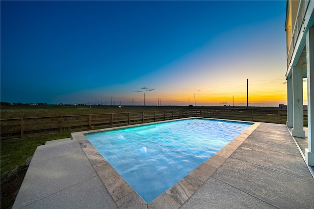 pool at dusk with a patio area