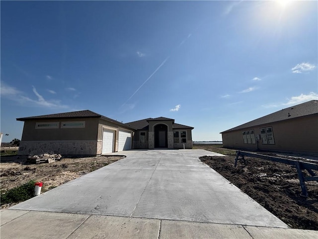 view of front of property with stone siding, concrete driveway, an attached garage, and stucco siding