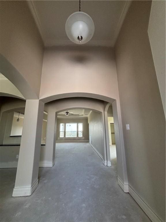 interior space with ornamental molding, arched walkways, concrete floors, and a towering ceiling