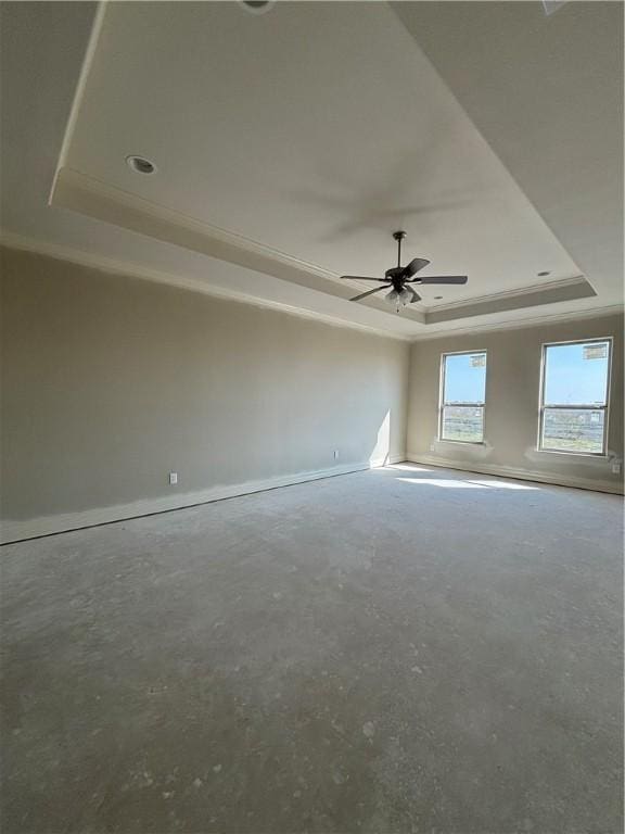 unfurnished room with a raised ceiling, a ceiling fan, and unfinished concrete floors