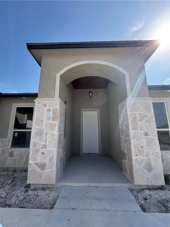 doorway to property featuring stone siding and stucco siding